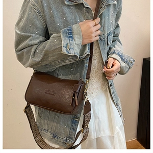 Détail du sac bandoulière vintage marron foncé avec une sangle tissée géométrique