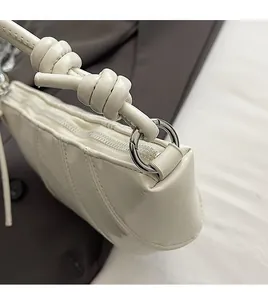 Close-up of a white leather dumpling bag featuring silver hardware and knot strap detail