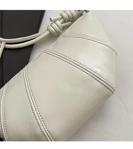Detail of off-white croissant bag showing premium leather texture and diagonal stitching