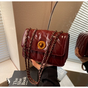 Détail du sac à main matelassé bordeaux avec fermoir doré et bandoulière en chaîne
