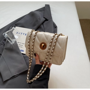 Gros plan du sac matelassé crème avec une bandoulière en chaîne dorée et fermoir