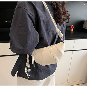 Detail of a beige PU leather dumpling bag with vertical stitching and knotted shoulder strap