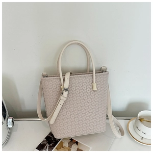 Dettaglio ravvicinato della borsa tote intrecciata color crema con finiture argentate