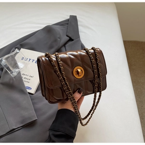 Détail d'un sac en cuir matelassé marron foncé avec un fermoir tournant doré