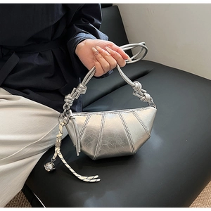 Detail of silver metallic pleated hobo bag with knotted handle and braided pendant charm