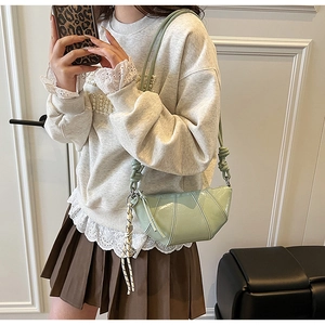 Detail of light green dumpling crossbody bag featuring pleated leather and knotted rope strap