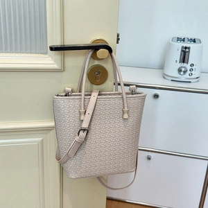 Dettaglio borsa a secchiello beige intrecciata con tracolla rimovibile e manici