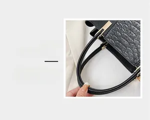Close-up of crocodile pattern texture on black tote bag with gold metal hardware