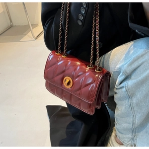Détail du sac bandoulière matelassé bordeaux avec chaîne dorée et fermoir rotatif