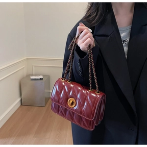 Vue détaillée du sac matelassé rouge vin avec chaîne dorée et fermoir rotatif