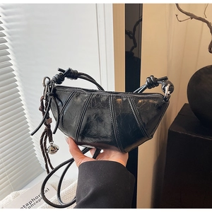 Detail of black crescent bag with oil wax leather texture and metallic charm