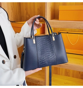 Detail of navy blue crocodile embossed leather tote with elegant golden hardware accents