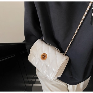 Gros plan d'un sac bandoulière blanc matelassé avec fermoir doré et bandoulière chaîne