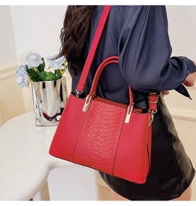 Detail view of red crocodile-pattern tote bag with gold hardware and shoulder strap