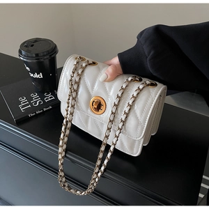Détail d'un sac matelassé beige avec fermoir doré et élégante bandoulière chaîne