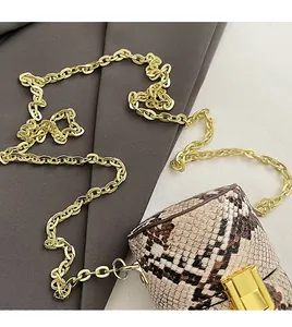 Détail macro du mini sac motif serpent avec chaîne dorée et fermoir métallique chic