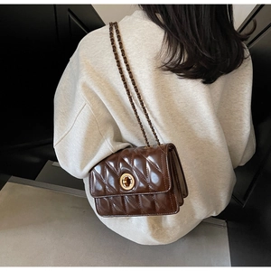 Détail du sac bandoulière matelassé marron foncé avec chaîne dorée et fermoir rotatif