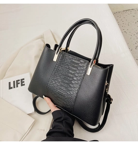 Detail showing crocodile texture and lychee grain leather stitching on black tote bag
