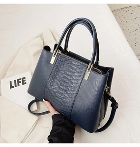 Detail of navy blue tote bag with crocodile pattern and golden metal zipper closure