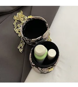 Détail de l'intérieur spacieux d'un mini sac cylindre en serpent avec chaîne dorée