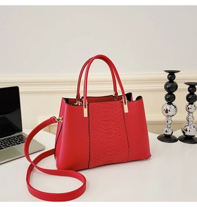 Detailed close-up of red crocodile pattern embossing on a luxury tote bag with gold hardware