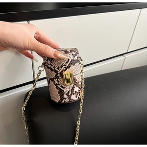 Détail d'un mini sac cylindrique avec motif serpent et bandoulière chaîne dorée