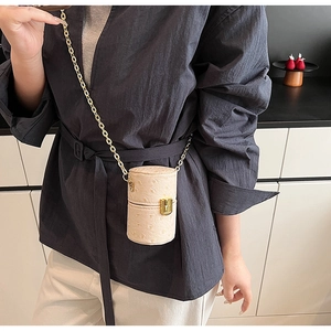 Détail d'un mini sac cylindre beige à motif autruche avec chaîne dorée et fermoir métal