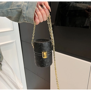 Détail du mini sac noir embossé autruche avec chaîne dorée et fermoir à poussoir