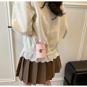 Détail du mini sac cylindrique rose avec texture autruche et bandoulière chaîne dorée