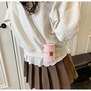 Mini sac cylindrique rose texture autruche avec bandoulière chaîne dorée sur modèle