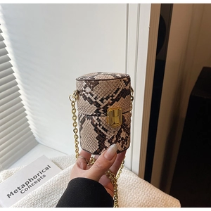 Gros plan du mini sac cylindrique avec texture serpent et chaîne dorée