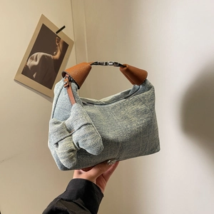 Fashionable denim pillow bag with brown leather handles and a side bow knot