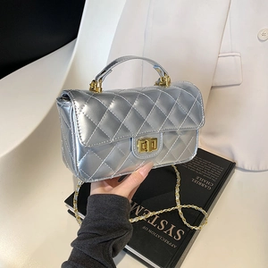 Quilted silver chain bag with gold ball charm shown in a stylish lifestyle setting