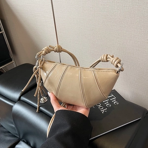 Quilted beige croissant shoulder bag with knotted handle and metallic ball charm