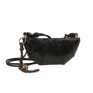 Glossy black pleated dumplings bag with rope handle and silver pendant on white backdrop