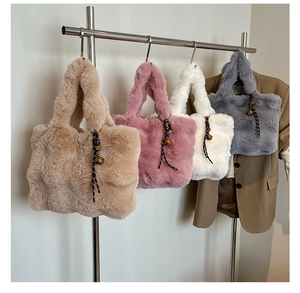 Detail of soft faux fur tote bags in khaki, pink, white, and gray with golden bell charms