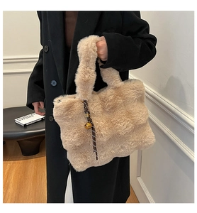 Detailed close-up of beige plush tote bag with decorative bell charm and fuzzy handle