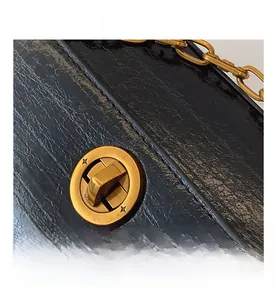 Detail of vintage gold star twist lock and lychee texture black leather underarm bag