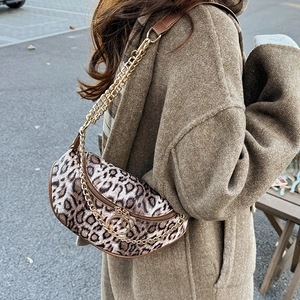Chic leopard print crescent underarm bag with gold chain strap in outdoor setting