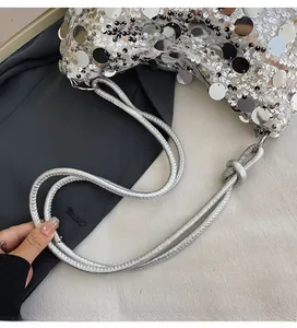 Macro shot of silver sequined handbag with smooth woven shoulder strap and knot detail