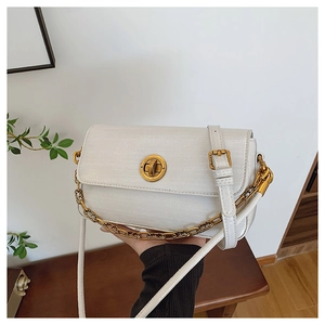 Detail of white litchi pattern leather bag with golden rotating lock and chain strap