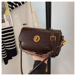 Macro detail of dark brown faux crocodile leather bag with gold buckle and chain