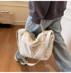 Détail du grand sac cabas en toile beige avec bandoulière réglable dans un décor moderne