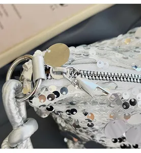 Detailed close-up of smooth silver metal zipper and shiny sequins on shoulder bag