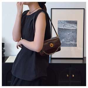 Close-up of wood-grain leather bag with gold buckle and chain in an elegant setting
