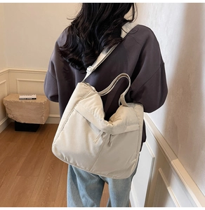 Détail d'un grand sac cabas en toile beige porté en sac à bandoulière élégant