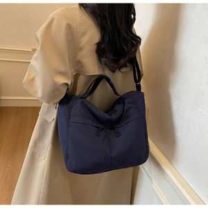 Détail du sac cabas en nylon bleu foncé avec poche zippée porté par un mannequin