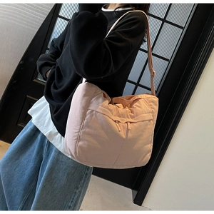 Gros plan d'un sac bandoulière rose matelassé porté avec une tenue décontractée