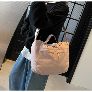 Détail d'un sac à bandoulière en nylon rose avec poche frontale zippée et sangle