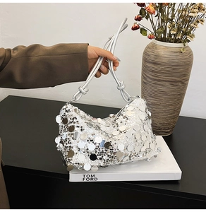 Detail of silver sequin handbag with metallic texture and knotted rope shoulder strap